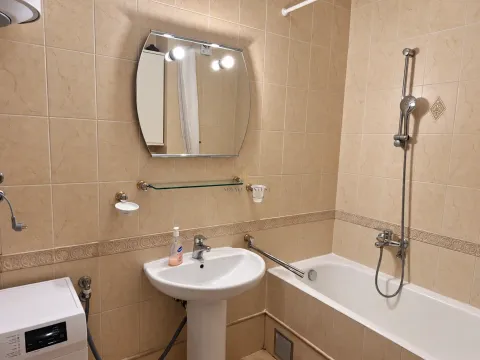 Kupatilo sa kadom, umivaonikom, ogledalom i mašinom za veš u bež pločicama. - image 7