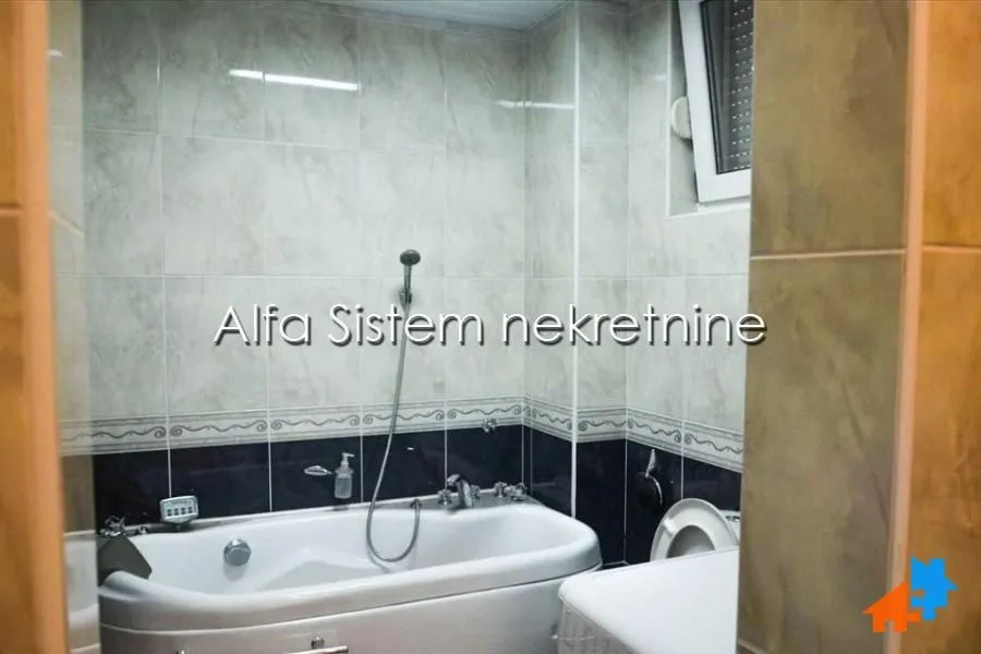 Smaller bathroom with a bathtub and tiles in light and dark tones.