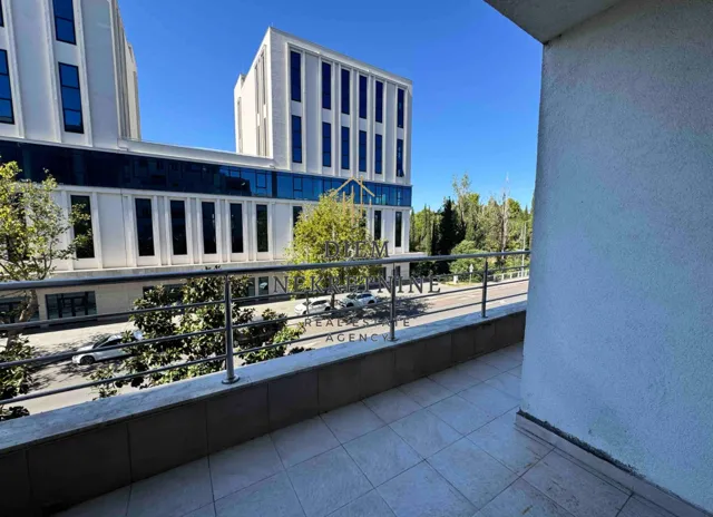 Natkrivena terasa sa pogledom na ulicu i moderne zgrade.