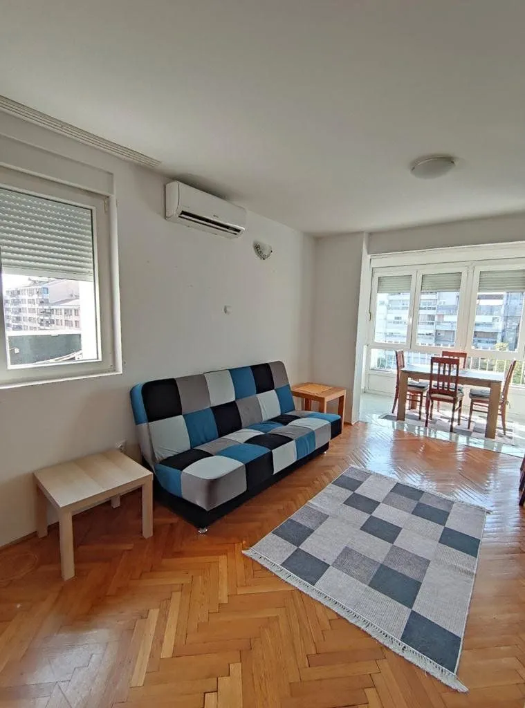 Living room with a sofa and a dining area in the background.