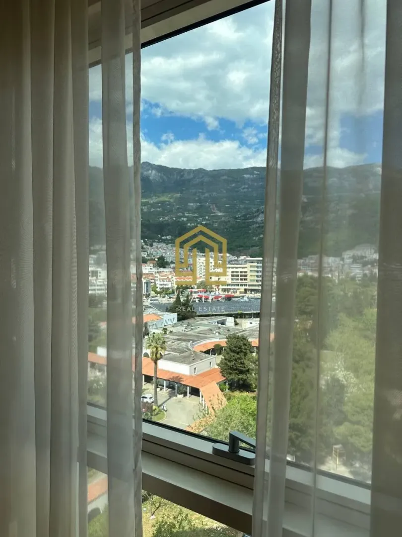 Pogled sa prozora na grad i planine kroz zavjese.