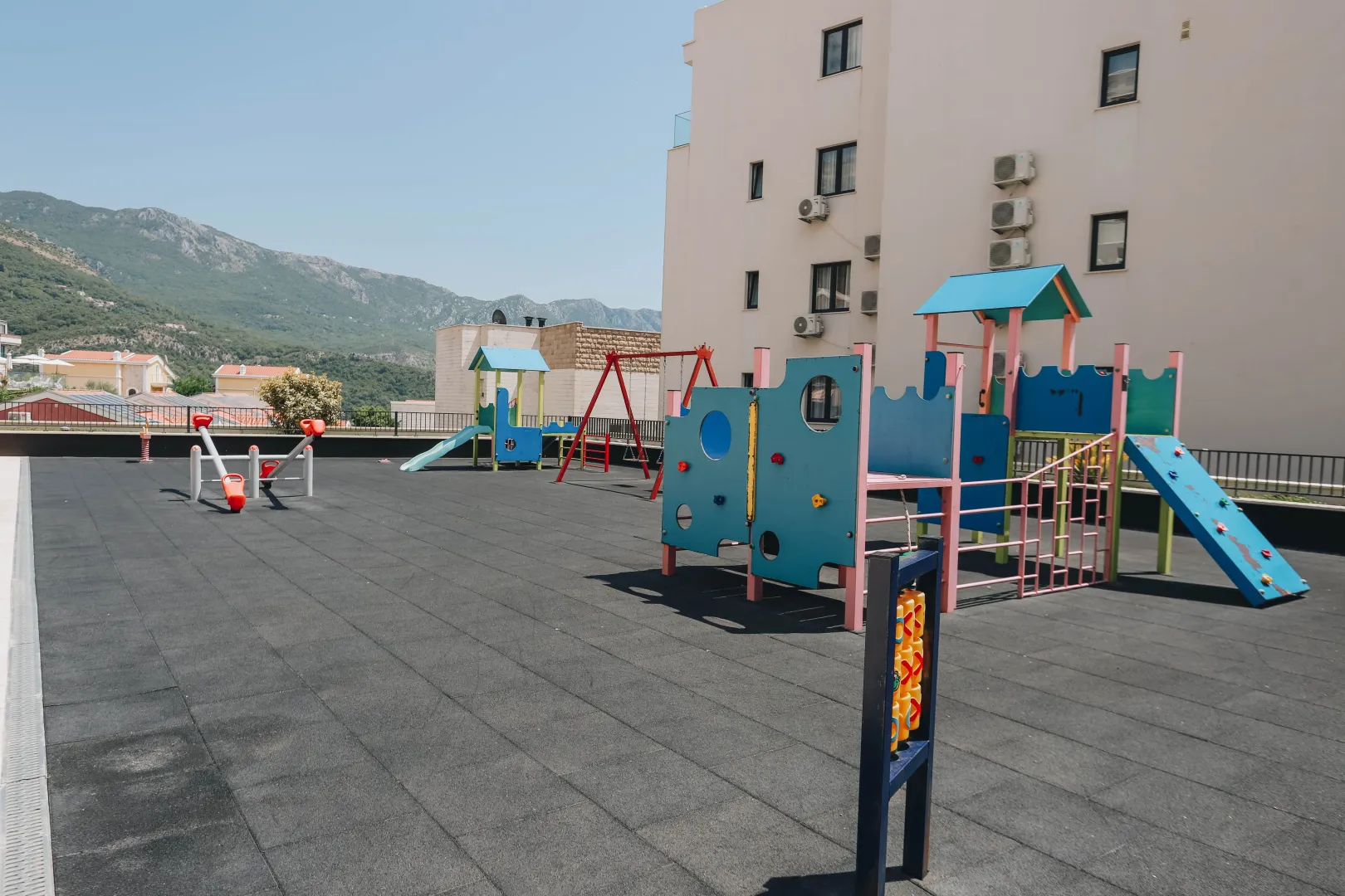 Children's playground in front of a residential building with a mountain view.