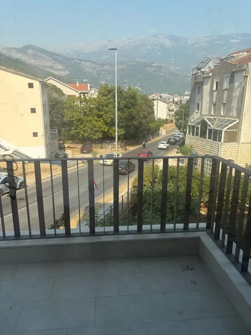 Pogled sa terase na ulicu i okolne zgrade sa planinama u pozadini.