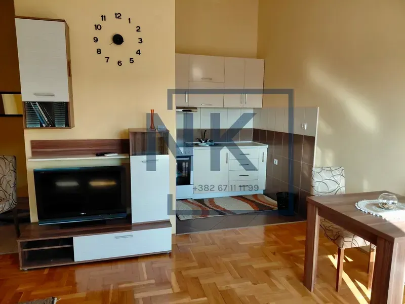 Dnevna soba sa kuhinjom, trpezarijom i televizorom.