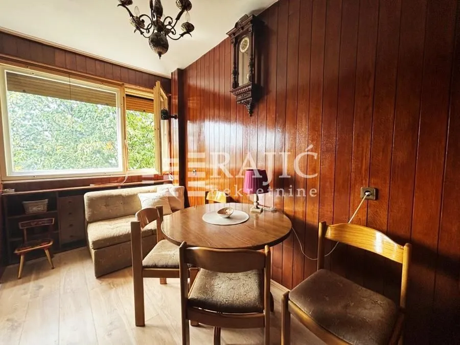 Living room with wood wall paneling and a dining table.