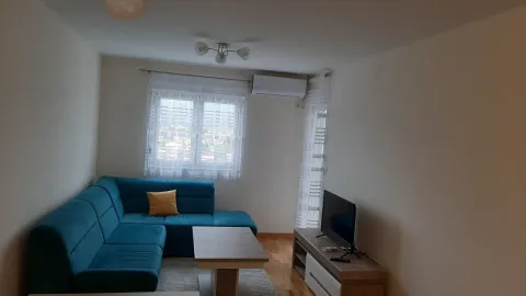 Svijetla dnevna soba sa plavom ugaonom garniturom i televizorom. - image 4