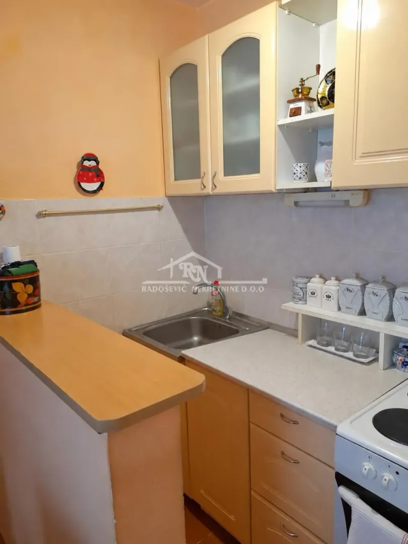 Manja kuhinja sa šankom, sudoperom i visećim elementima.