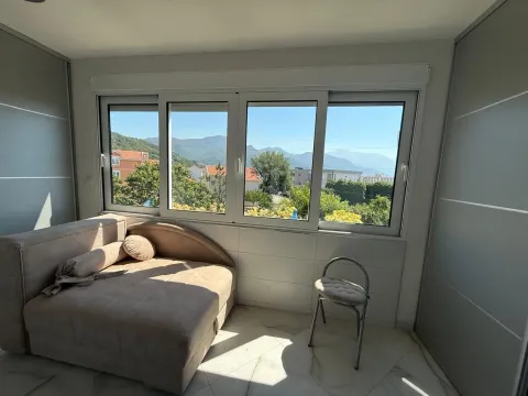Manja spavaća soba sa krevetom i pogledom na prirodu i okolne kuće kroz veliki prozor. - image 10