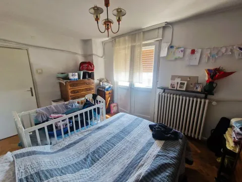Spavaća soba sa bračnim krevetom, krevetcem za bebe i nameštajem. - image 13
