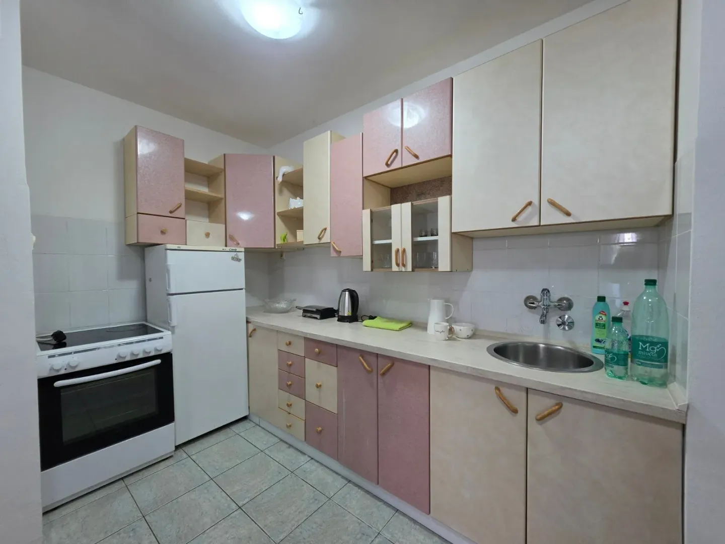 Kitchen with a sink, stove, refrigerator, and wooden cabinetry.