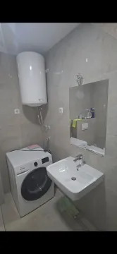 Modern bathroom with a sink, mirror, water heater, and washing machine. - image 18