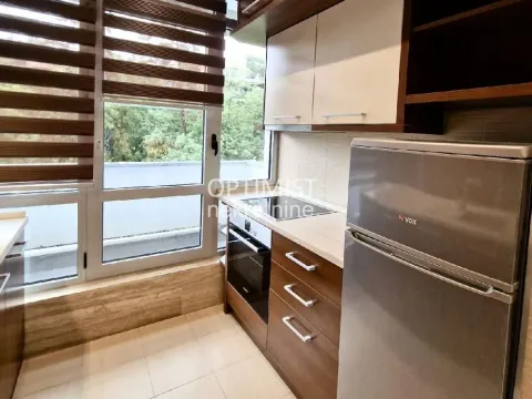 Small kitchen with wooden cabinets, refrigerator, and a window overlooking the terrace. - image 4