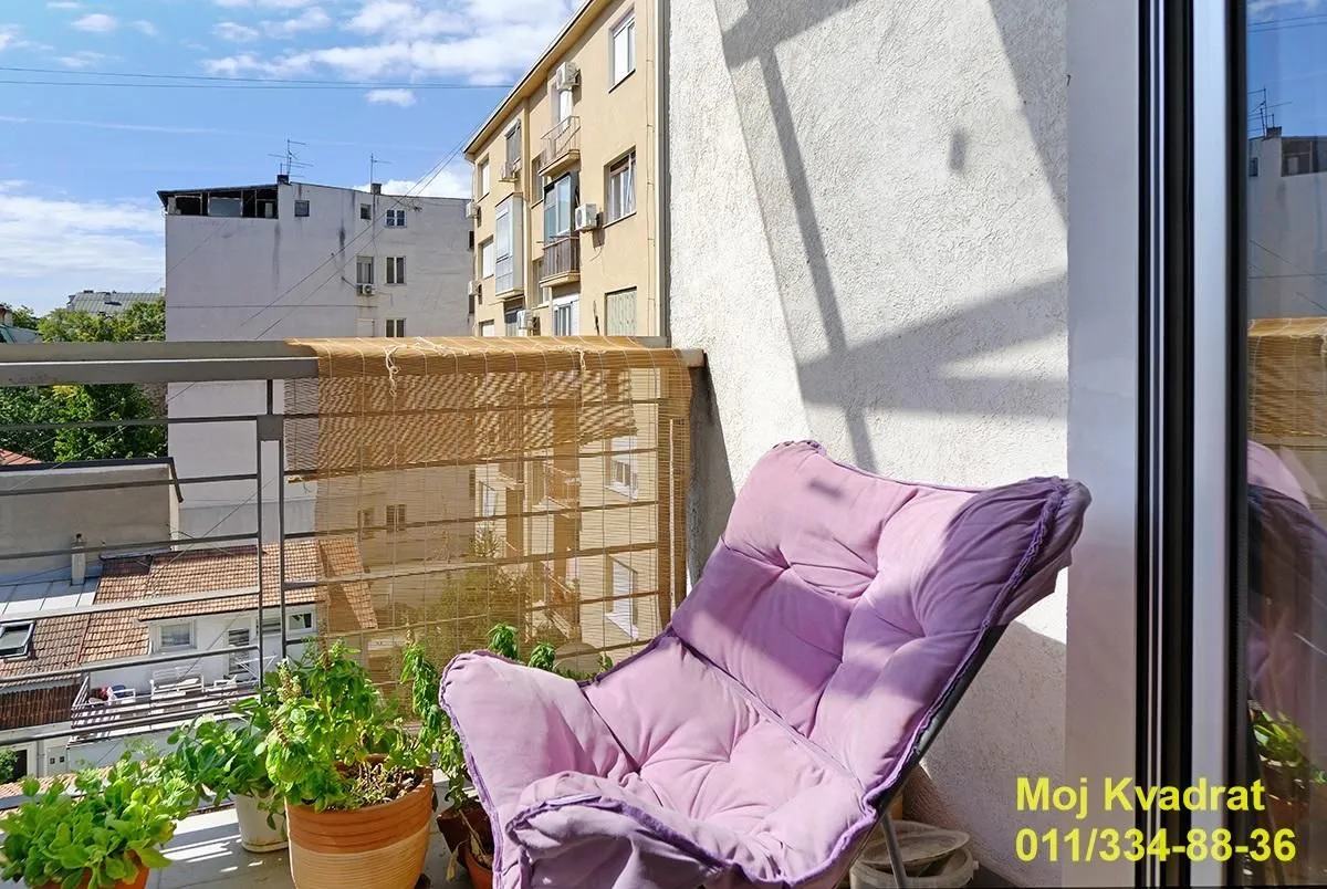 Manji namešteni balkon sa stolicom i zelenilom.