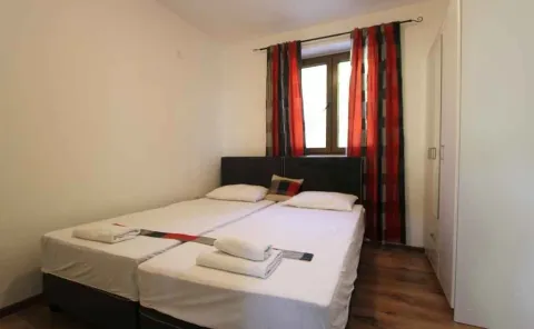 Jednostavno namještena spavaća soba sa dva spojena kreveta i bijelim ormarom. - image 18