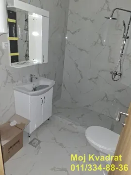 Novoopremljeno kupatilo sa umivaonikom, tuš kabinom i belim keramičkim pločicama. - image 8