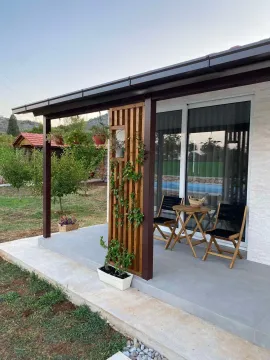 Covered terrace with a wooden table and chairs in front of the house. - image 11