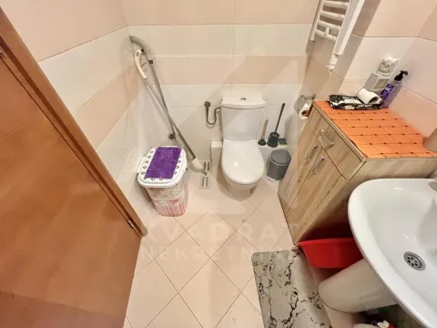 Small bathroom with a toilet, washbasin, and wooden cabinet. - image 10