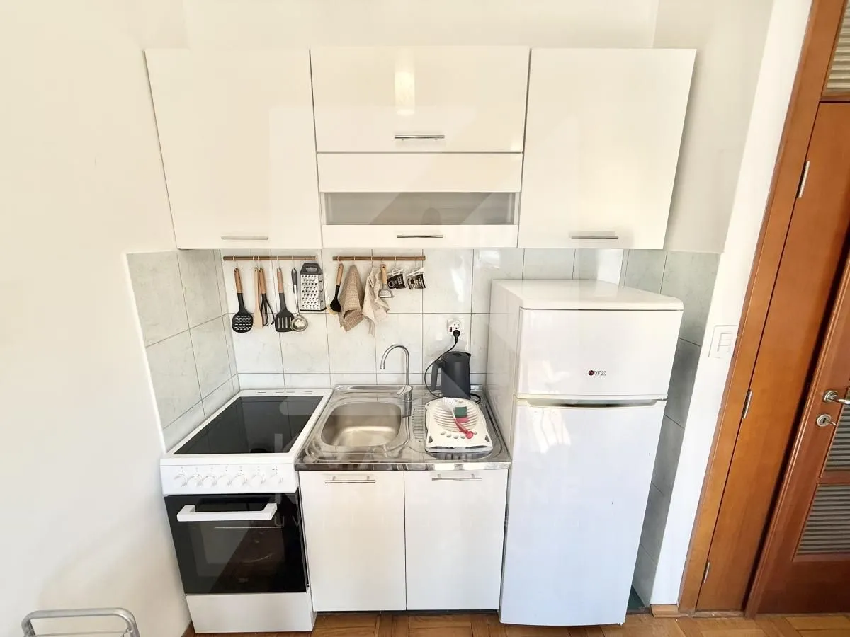Small white kitchen with a stove, sink, and refrigerator.