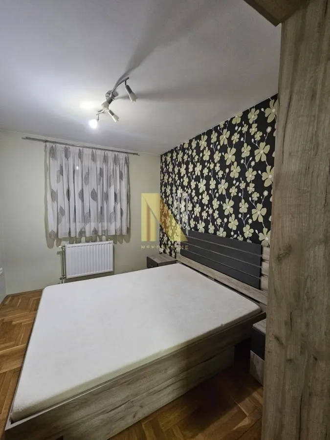 Nameštena spavaća soba sa bračnim krevetom i tapetom na zidu.