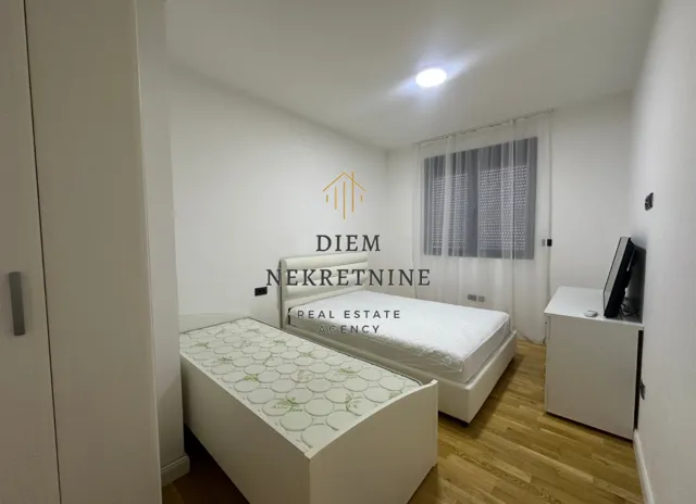 Furnished bedroom with two beds and a white wardrobe.