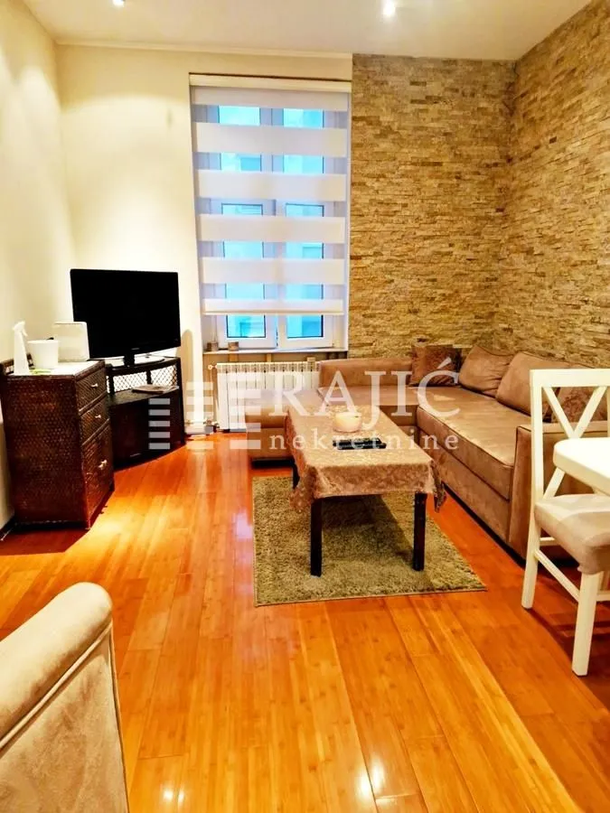 Living room with sofa, wooden flooring, and a decorative stone accent wall.