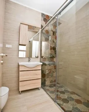 Modernly equipped bathroom with a walk-in shower and vanity unit. - image 8