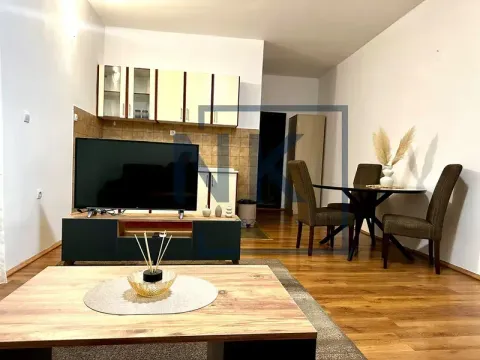 Living room with a TV unit and dining table, with a kitchen visible in the background. - image 2
