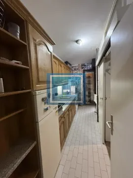 Narrow kitchen with wooden cabinets and white tiled floor. - image 9