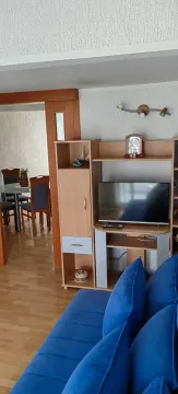 Dnevna soba sa plavom garniturom i TV komodom, sa pogledom na trpezariju. - image 3