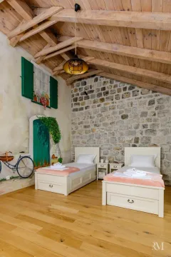 Bedroom with two single beds, stone wall, and wooden ceiling. - image 10