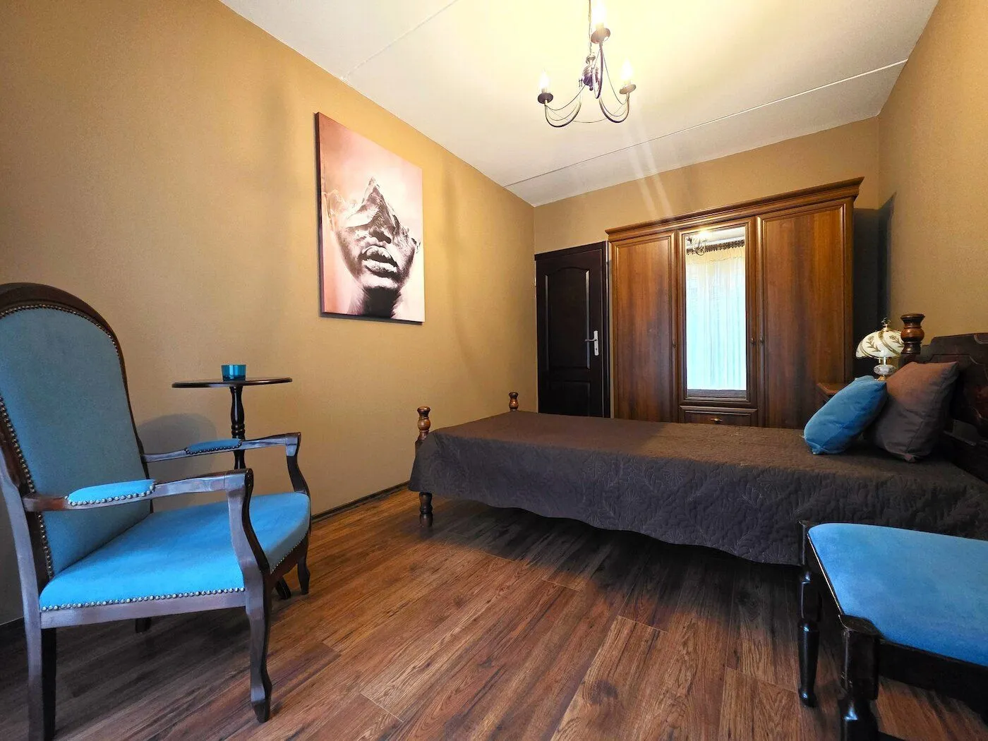 Furnished bedroom with a bed, wooden wardrobe, and blue armchairs.