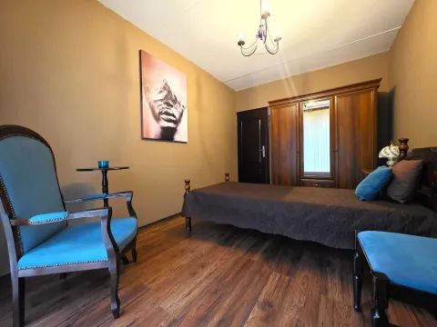 Furnished bedroom with a bed, wooden wardrobe, and blue armchairs. - image 10