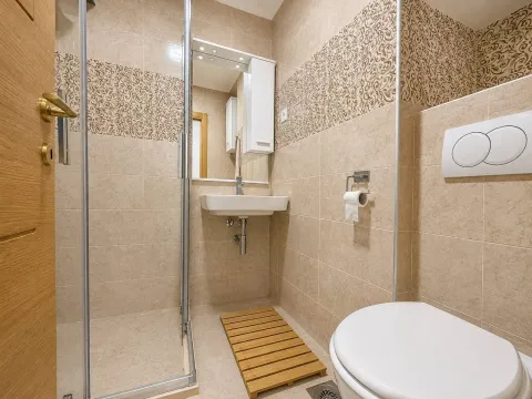 Small bathroom with a shower cabin, sink, and toilet. - image 6