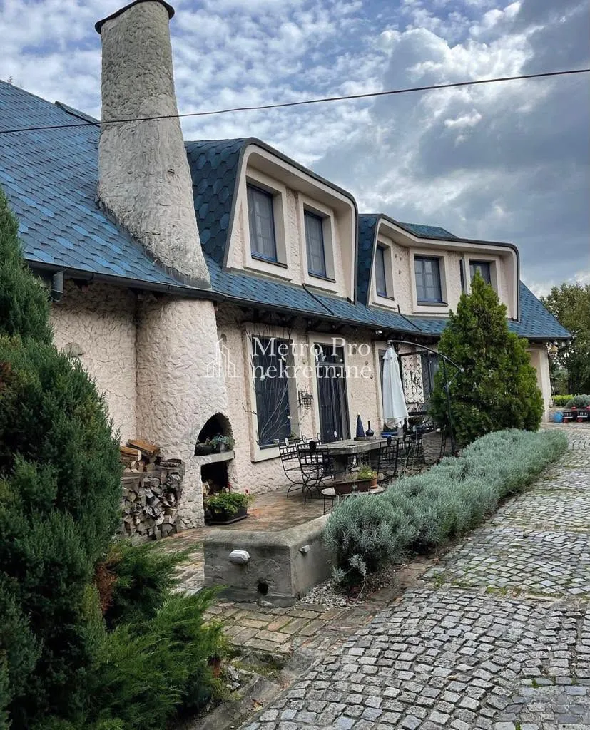 Pogled na dvorište i spoljašnjost kuće sa popločanim dvorištem.