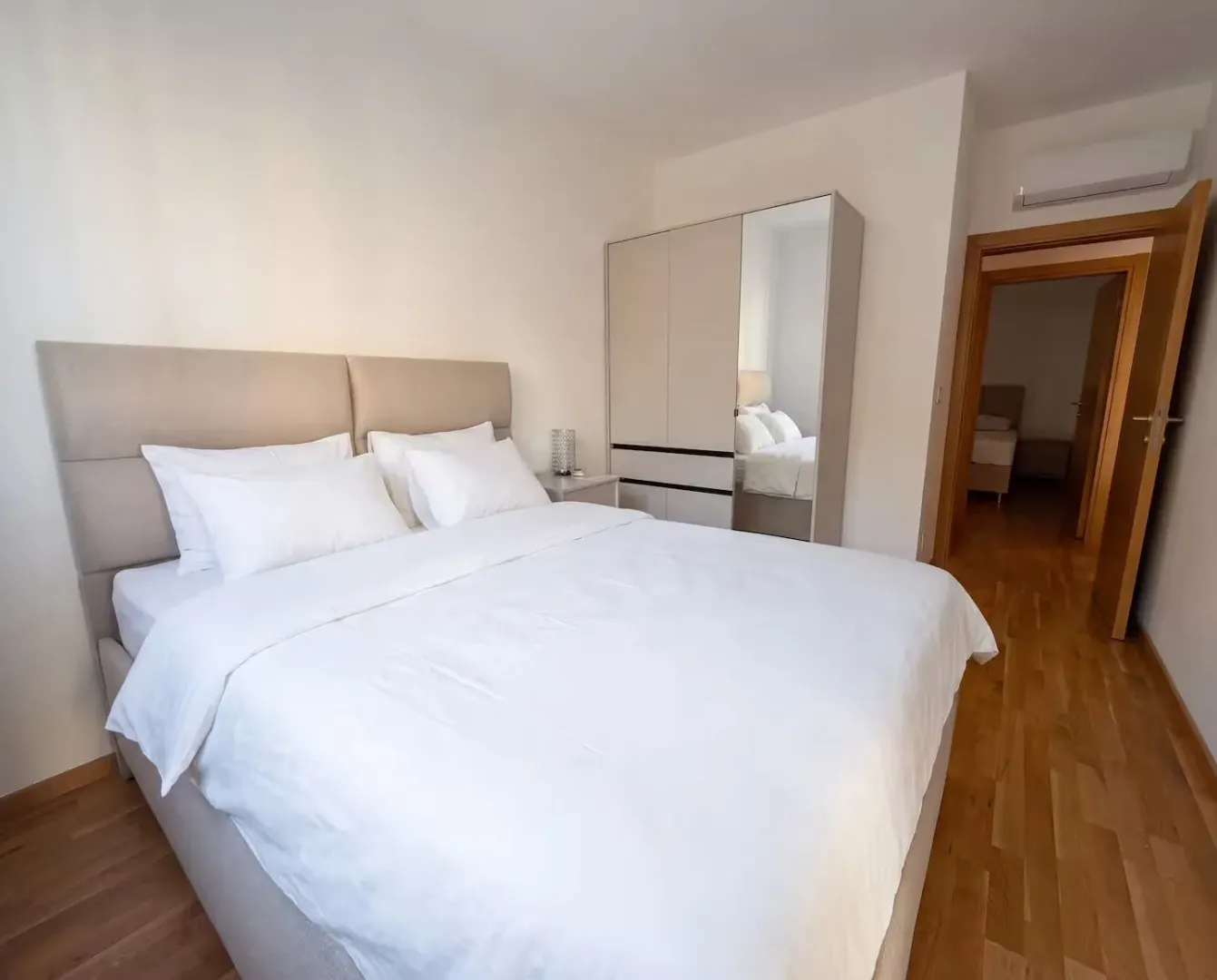 Bedroom with a double bed, mirrored wardrobe, and hardwood flooring.