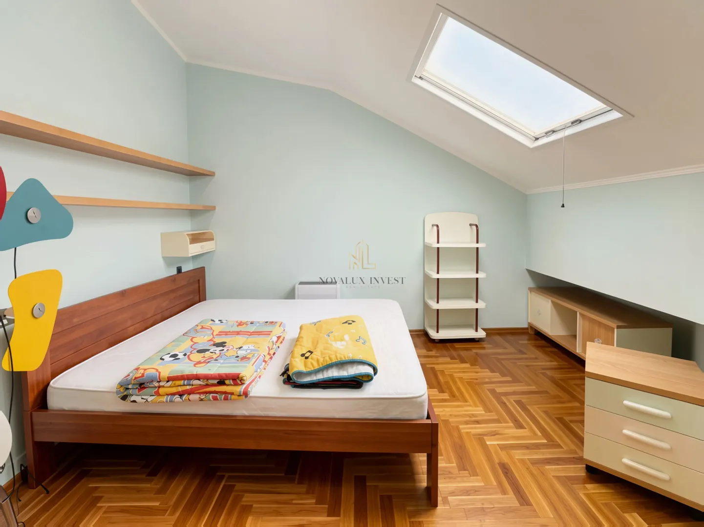 Children's bedroom with a wooden bed and a skylight.