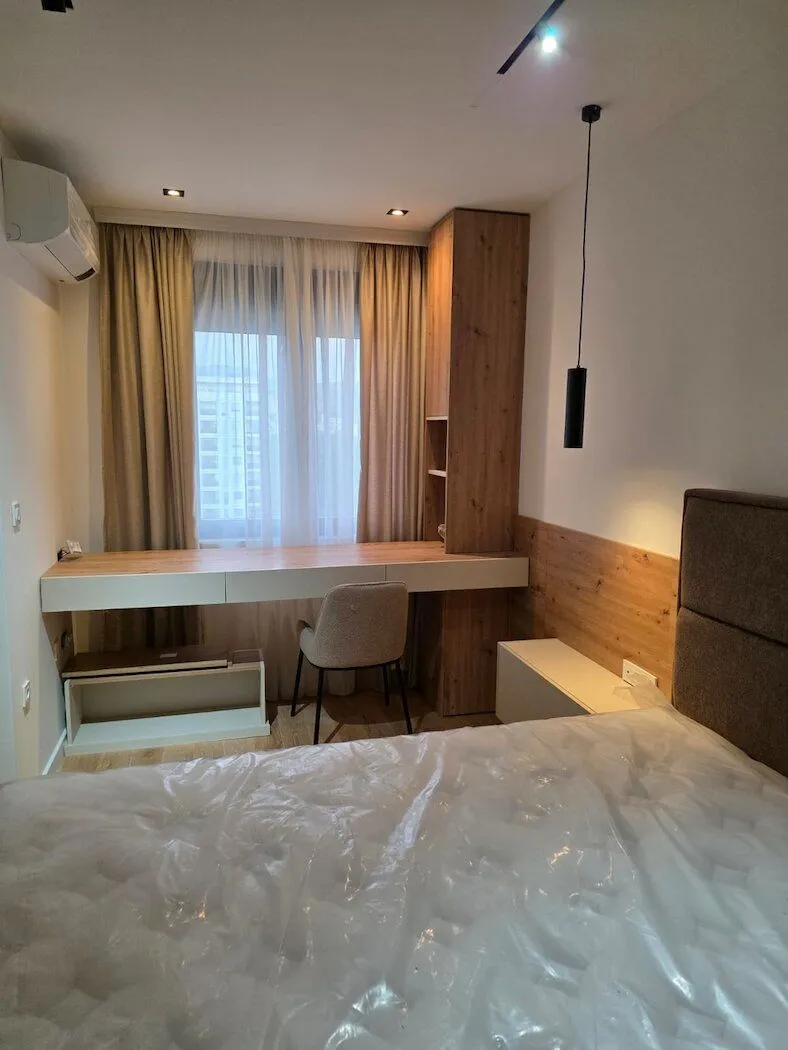 A bedroom with a double bed, a desk, and a wardrobe.