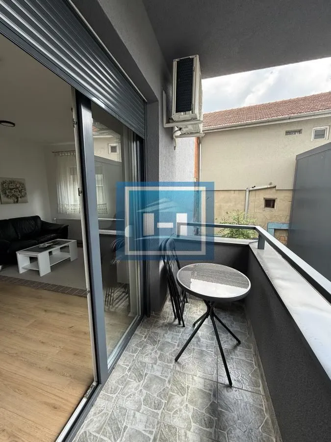 Small furnished balcony with a table and chairs, accessible from the living room.