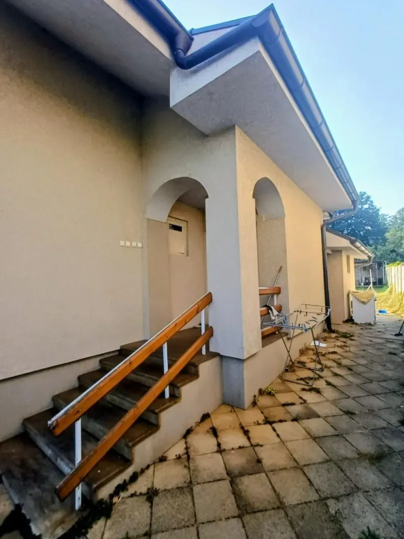 Pogled na spoljašnjost kuće sa ulaznim stepeništem i popločanim dvorištem.