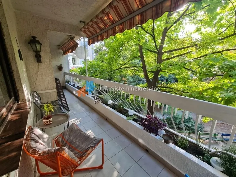 Spacious balcony with seating furniture and a green view.