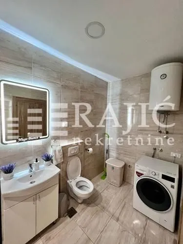 Modernly equipped bathroom with a washbasin, toilet, and washing machine.