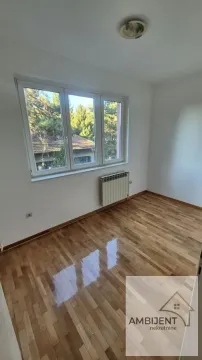 Prazna soba sa parketom i prozorom koji gleda na zelenilo. - image 7