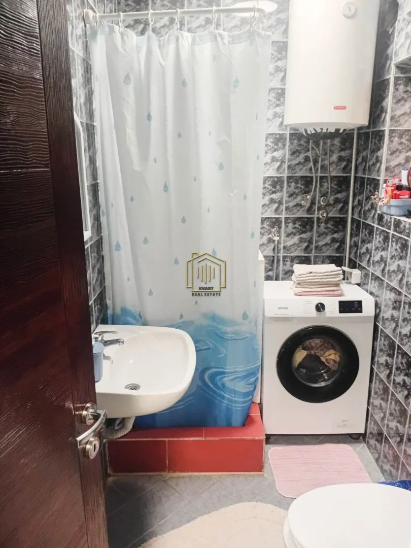 Smaller bathroom with a shower cabin, washbasin, and washing machine.