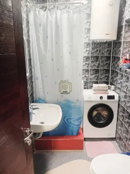Smaller bathroom with a shower cabin, washbasin, and washing machine. - image 6