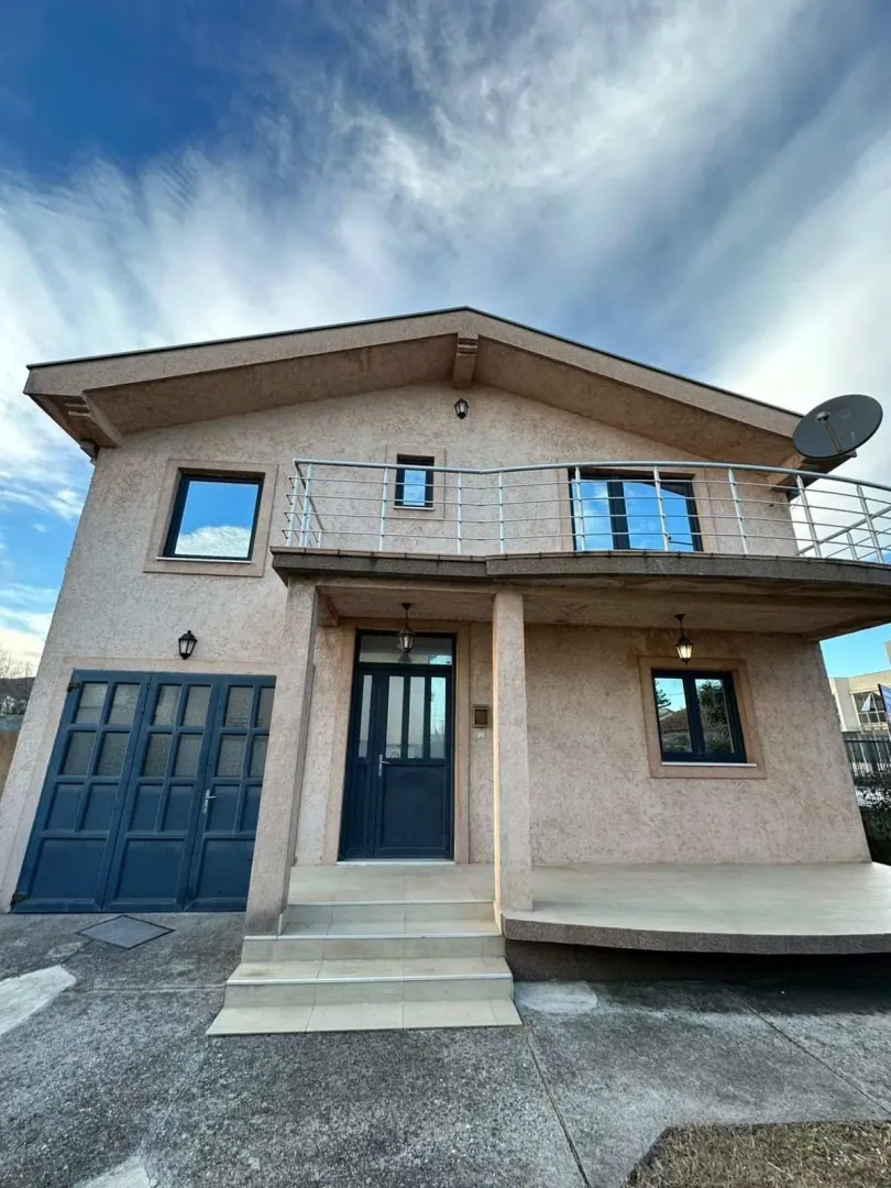Exterior view of a family house featuring a garage and a spacious balcony.