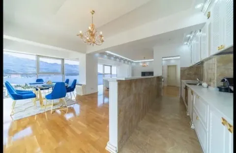 Spacious living room with a dining area, kitchen, and large windows offering a sea view. - image 16