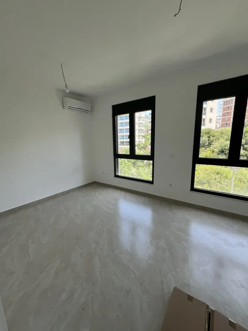 An empty and bright room with large windows and tiled flooring.