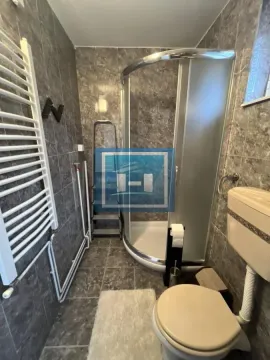 Manje kupatilo obloženo tamnim pločicama sa tuš kabinom i wc šoljom. - image 16
