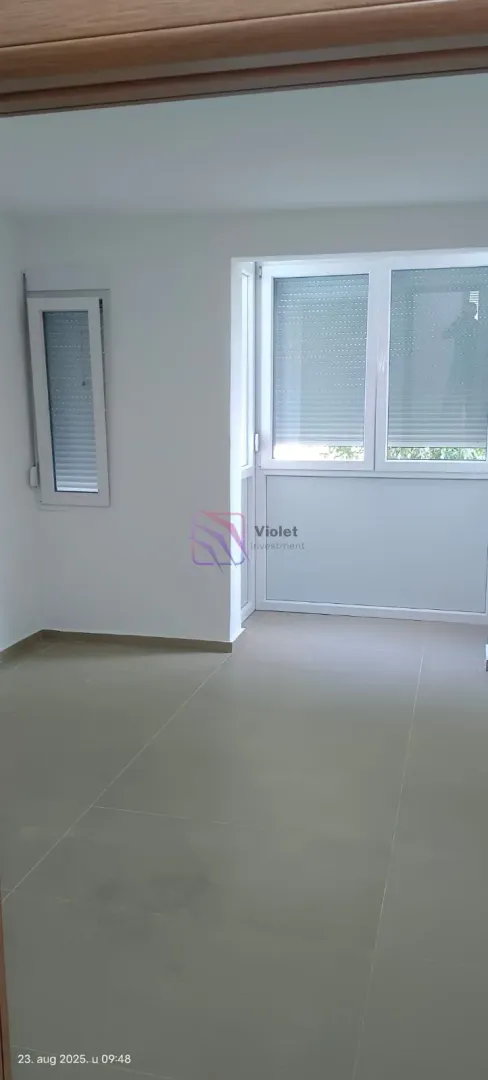 Empty room with ceramic tiles and windows with shutters.