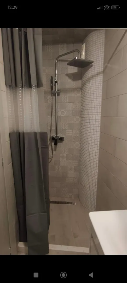 Shower enclosure with a curtain and modern faucet in the bathroom.